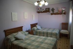 a bedroom with two beds and a chair and a lamp at ApartamentoLillos in Luanco