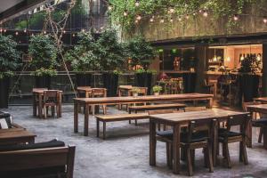 um restaurante com mesas de madeira, cadeiras e plantas em Anselmo Buenos Aires, Curio Collection by Hilton em Buenos Aires