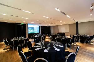 una sala de conferencias con mesas, sillas y una pantalla en Anselmo Buenos Aires, Curio Collection by Hilton en Buenos Aires