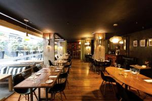 a restaurant with wooden tables and chairs and a large window at Anselmo Buenos Aires, Curio Collection by Hilton in Buenos Aires