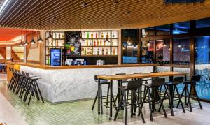 eine Bar mit Holztischen und Barhockern in der Unterkunft Hampton by Hilton Guarulhos Airport in Guarulhos