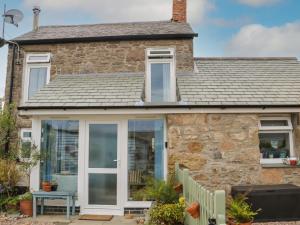 a stone house with a conservatory and sliding glass doors at Flintstone Cottage in Penzance