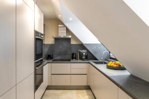 kuchnia z białymi szafkami, zlewem i schodami w obiekcie Beautiful 2-Bed Apartment in London w Londynie