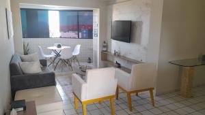 a living room with two white chairs and a table at apto confortável em Pirangi do Norte in Parnamirim