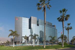 a large glass building with palm trees in front of it at Hilton Garden Inn Iquique in Iquique