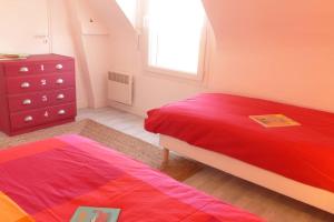 a bedroom with a red bed and a dresser at Ty Kerigan, Maison 3* proche de la plage - Locmariaquer in Locmariaquer