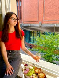 una mujer sosteniendo una copa de vino junto a un plato de comida en Apartamenty Browar Luxury Old Town Poznań Check In 24h, en Poznan