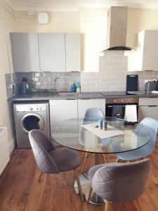 cocina con mesa de cristal y sillas en 2 Bedroom Apartment 2 Min Walk to Station - longer stays available, en Gravesend