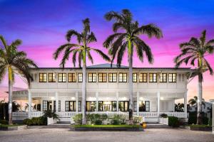 a large white building with palm trees in front of it at Mahogany Bay Resort and Beach Club, Curio Collection in San Pedro