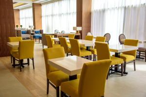a dining room with tables and yellow chairs at Hampton Inn Piedras Negras in Piedras Negras