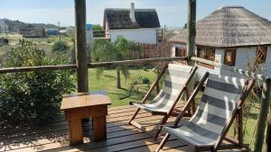 zwei Stühle und ein Tisch auf einem Holzdeck in der Unterkunft Moana in Punta Del Diablo