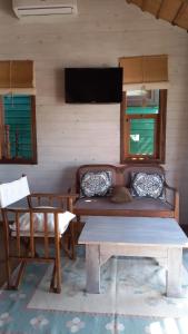 ein Sofa in einem Zimmer mit einem Tisch und einem TV in der Unterkunft Moana in Punta Del Diablo