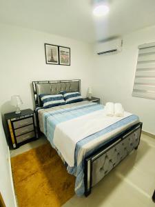 um quarto com uma cama grande com lençóis azuis e brancos em Confortable y lujoso apartamento en santiago em Santiago de los Caballeros