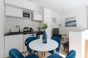cocina con mesa blanca y sillas azules en sousplex Cosy - proche tram et Corum - CLIM, en Montpellier