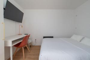 1 dormitorio con cama blanca y escritorio con silla roja en sousplex Cosy - proche tram et Corum - CLIM, en Montpellier