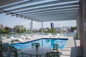 un patio con mesa, sillas y piscina en Hilton Garden Inn Leon Poliforum, en León