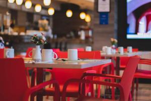 a restaurant with red chairs and tables with flowers on them at Hilton Garden Inn Leon Poliforum in León +12 photos