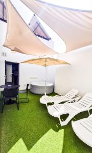 a room with green carpet and white chairs and an umbrella at Atypicap Capsule Hostel in Puerto de la Cruz