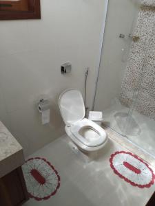 a bathroom with a toilet with red and white rugs at Sítio Olho de Boneca in Itamonte