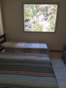 Schlafzimmer mit einem Bett und einem großen Fenster in der Unterkunft Sítio Olho de Boneca in Itamonte