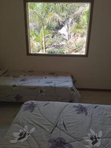 2 Betten in einem Zimmer mit Fenster in der Unterkunft Sítio Olho de Boneca in Itamonte