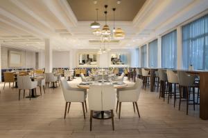 a dining room with tables and white chairs and windows at Casablanca Marriott Hotel in Casablanca