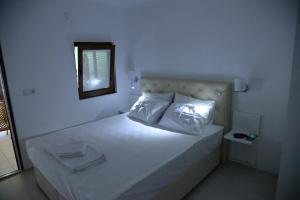 Schlafzimmer mit einem Bett mit weißer Bettwäsche und einem Spiegel in der Unterkunft Chiyanno's Inn in Dalyanköy