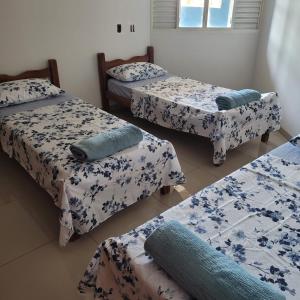 a room with three beds with blue and white sheets at Hostel da Spipe in Campo Grande