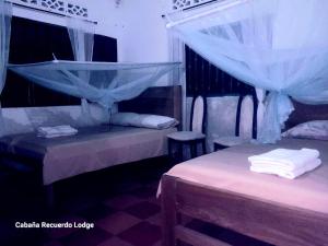 1 dormitorio con 2 camas con mosquiteras en Cabaña RECUERDO Lodge, B & B en Moñitos
