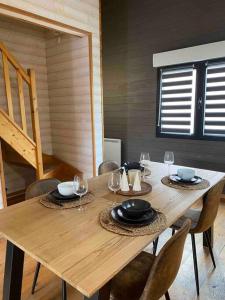 a wooden table with chairs and plates and wine glasses at Le Chalet de l'Abbé : magnifique maison chaleureuse in Cambrai