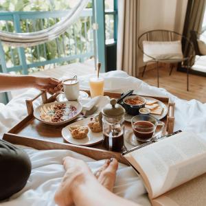 eine Person im Bett mit einem Tablett mit Essen und einem Buch in der Unterkunft Hotel Plantación in Jardin