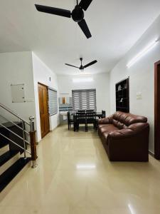 ein Wohnzimmer mit einem Sofa und einem Deckenventilator in der Unterkunft Saaketh Holiday Home in Kozhikode