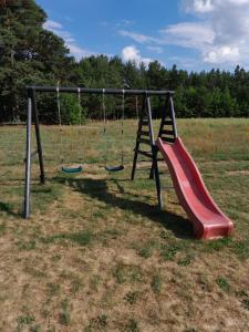 a playground with a red slide in a field at Domki letniskowe Jastrzębna in Sztabin