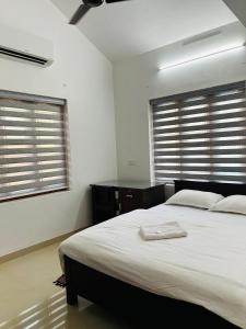ein Schlafzimmer mit einem großen Bett und zwei Fenstern in der Unterkunft Saaketh Holiday Home in Kozhikode