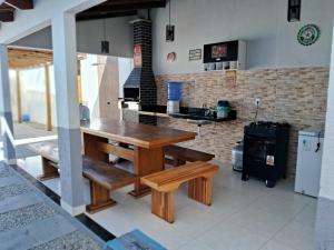 a kitchen with a wooden table and benches and a stove at Casa com piscina e espaço gourmet a 30m da praia! in Alcobaça