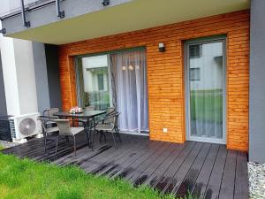 a wooden deck with a table and chairs on it at Apartament Sosnowy z dwoma sypialniami i ogródkiem in Ustroń