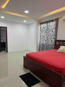 a bedroom with a bed with a red bedspread and a wall at Casa grande familiar Crucita in Crucita