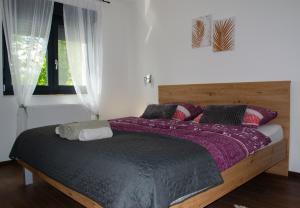 a bedroom with a large bed with purple sheets and a window at Kraljeva hiža - Apartmani i sobe Kralj in Sveti Martin na Muri
