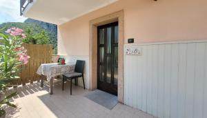 eine Terrasse mit einem Tisch und einer Tür mit einem Schild, das lächelt in der Unterkunft Maison AnnaBelle in Ceniga