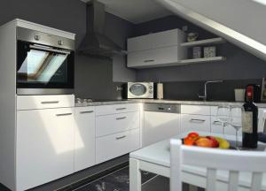 a kitchen with white cabinets and a table with a bowl of fruit at FeWo Schmeer - Köllerbach in Püttlingen