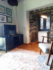 a living room with a tv and a chair at Casa Yañez in Chantada
