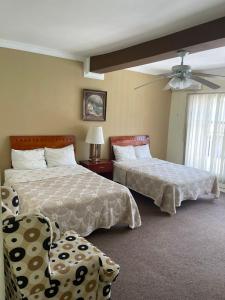 een slaapkamer met 2 bedden en een plafondventilator bij Hotel Rincon Real Suites in Durango