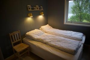 a bed in a room with a window and a chair at Hus i Sør-Tverrfjord 