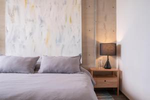 a bed with white sheets and a lamp on a night stand at Galeria Flat Rooftop Pool Witgdl in Guadalajara