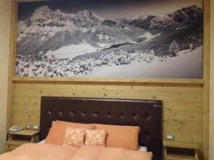 a bedroom with a large painting above a bed at Hotel Lavaredo in Misurina