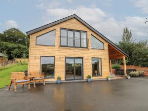 uma casa com uma mesa de piquenique e um banco em Harp Meadow em Presteigne