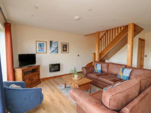 a living room with a couch and a tv at Harp Meadow in Presteigne