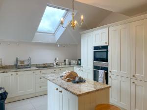 a kitchen with white cabinets and a skylight at Church End Cottage, Brampton in Brampton