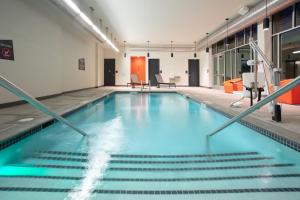 a swimming pool with blue water in a building at Aloft Omaha Aksarben Village in Omaha