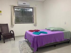 uma cama com um cobertor roxo num quarto com uma janela em pousada Cantinho da mata em Paraty